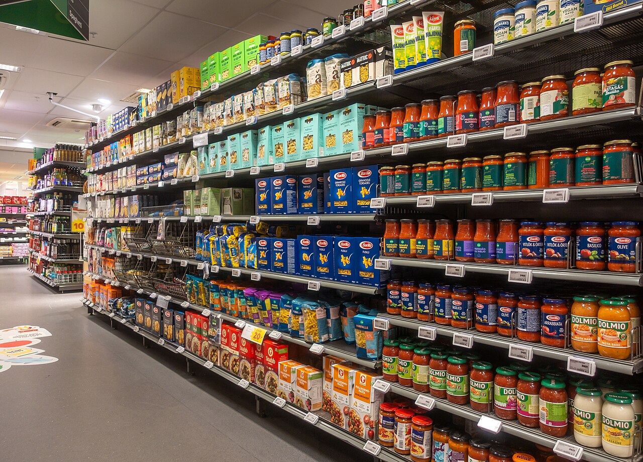 A 21st-century supermarket aisle stacked with packaged goods, the same errand a century later