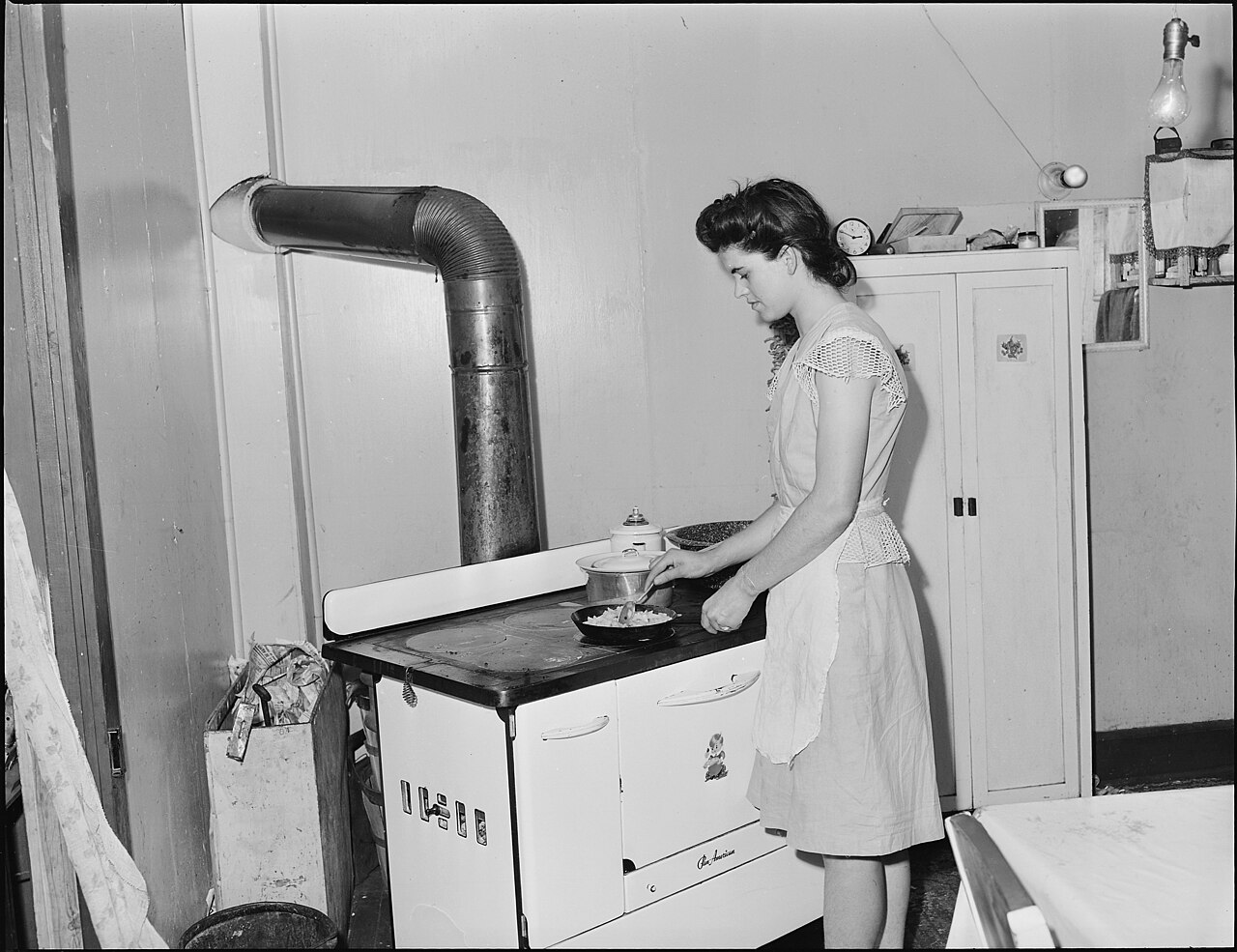 A woman in her kitchen in a four room house, the mid-century American home where the 1950s housewife full-time job was carried out