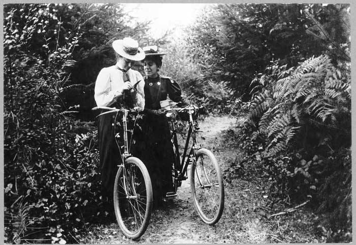 Rest cure era: two women in straw boater hats standing with their bicycles on a forest path, 24 August 1898, black and white